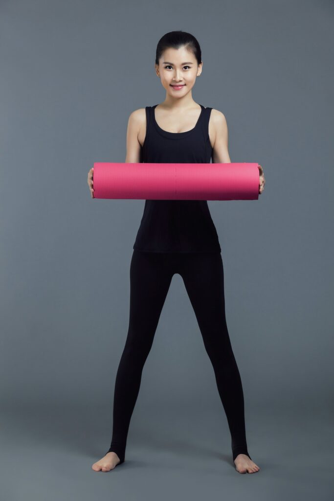 women holding rolled yoga mat