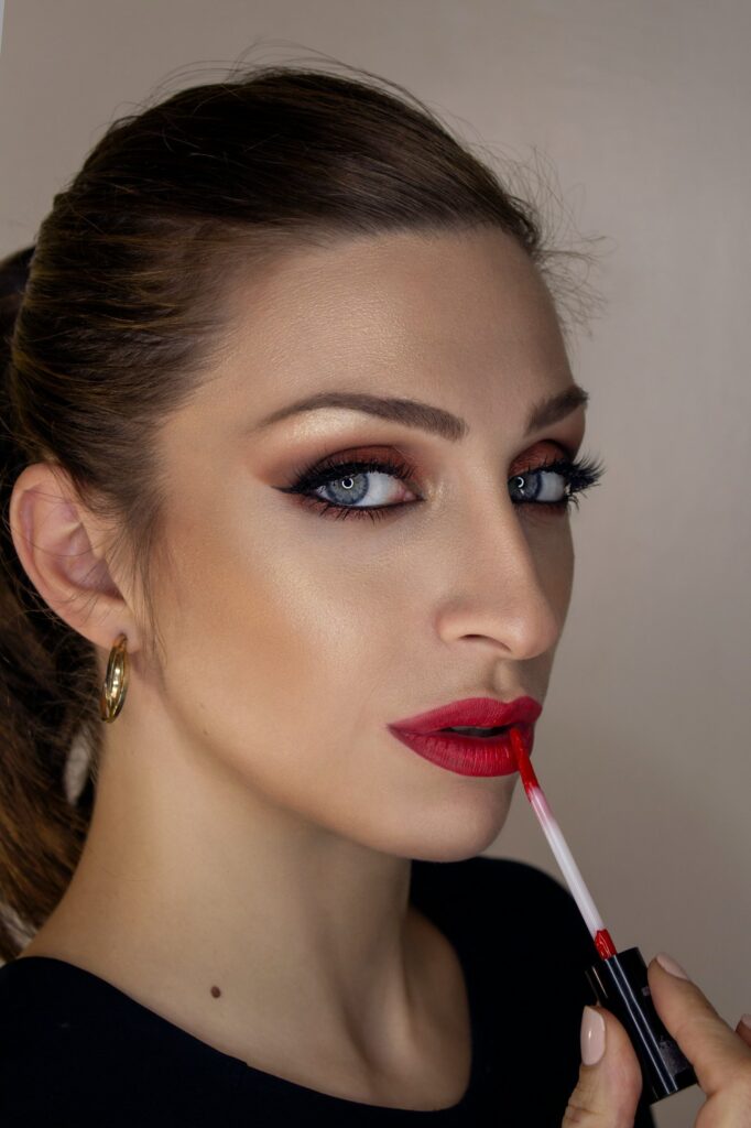 women holding lipstick applier with makeup