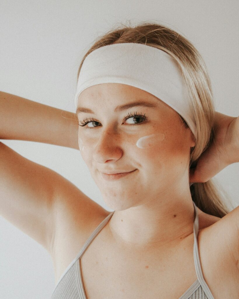 women wearing headband with moisturizer on cheeks
