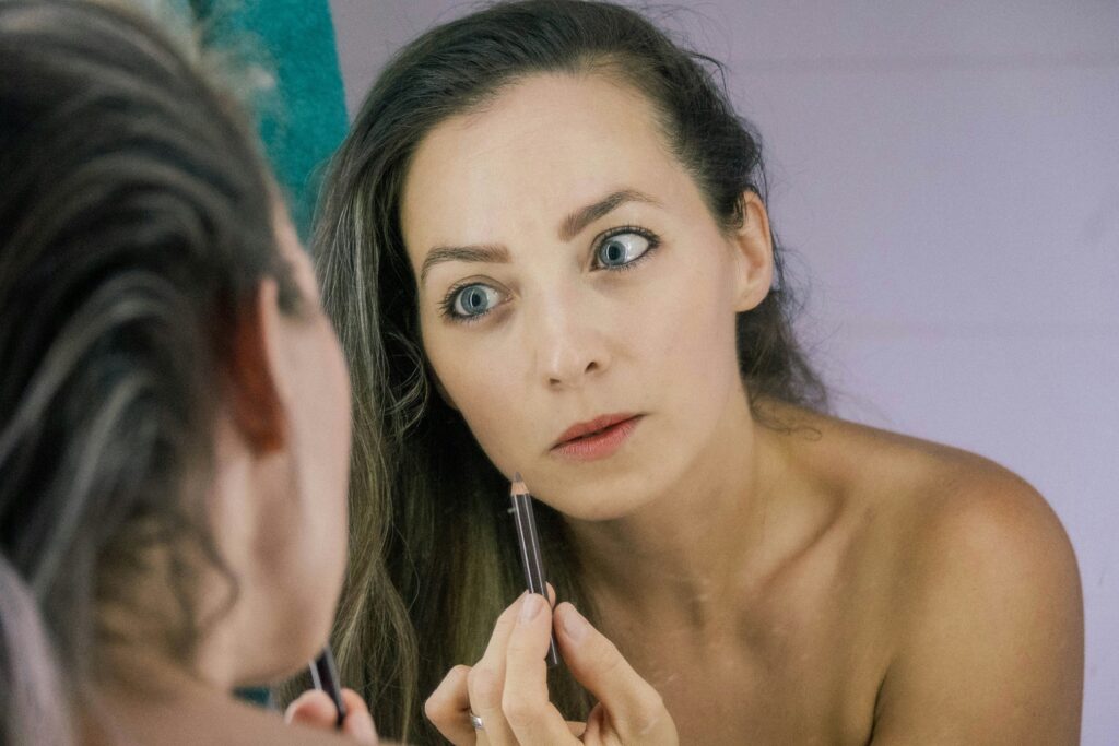 women applying skin product infront of mirror