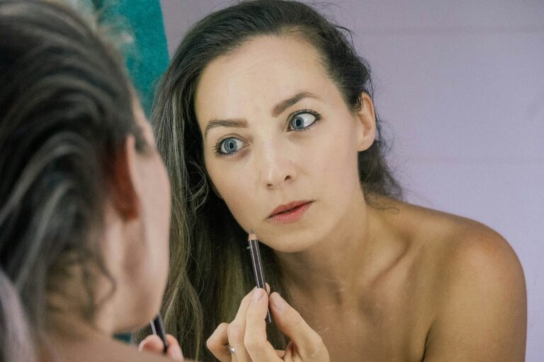 women applying skin product infront of mirror