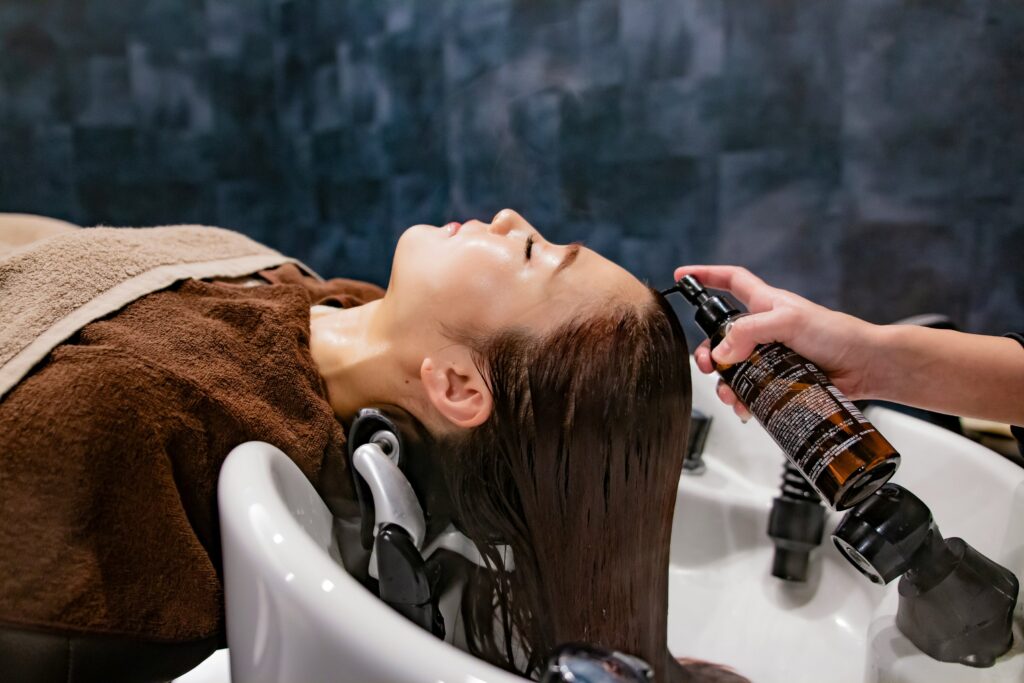 women lying with her head resting on a tub getting hair washed
